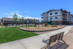 a park with a swing set and a bench in front of a building at InterUrban Apartments, Billings, 59106