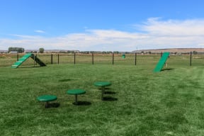 a playground with a slide and stools in a grassy area at InterUrban Apartments, Billings Montana