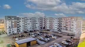 A large apartment complex with a parking lot in front.