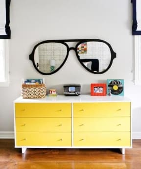 a dresser with a large pair of glasses on the wall
