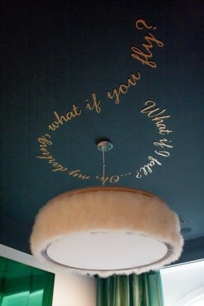 a black wall with writing on it and a lamp