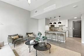 A modern living room with a kitchen in the background.