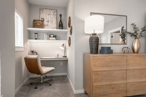 A well-lit room with a desk, chair, and a large mirror.
