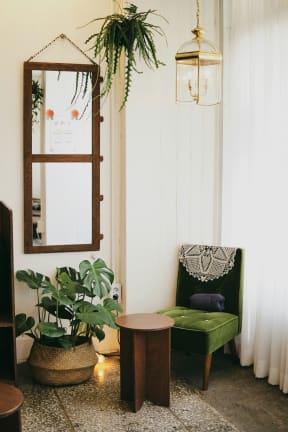 a living room with a green chair and a mirror