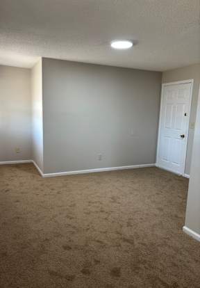 A room with a carpeted floor and a white door.