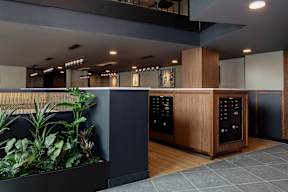 A modern office lobby with a reception desk and a planter with green plants.
