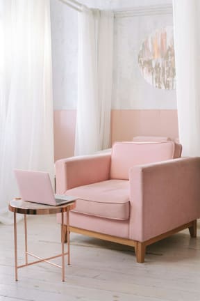 a living room with a pink couch and a laptop on a table