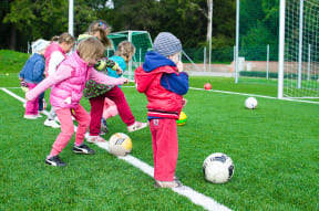 a group of young children kicking soccer balls on a field