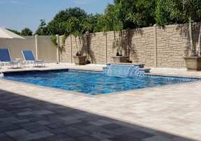 A pool with a waterfall and a stone wall.