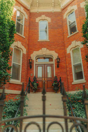 A red brick building with a wooden door and windows.