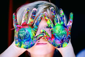 a woman holding her hands up with paint on them