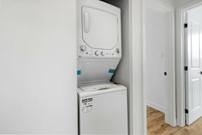 A white dryer is installed in a wall next to a white door.