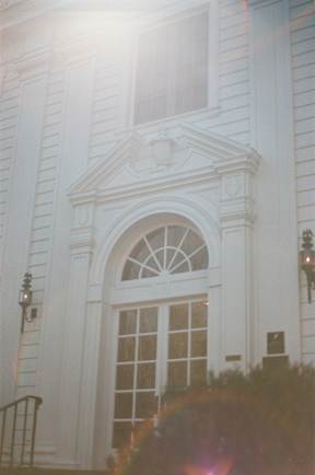A white building with a large arched doorway and a small window above it.
