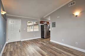 A kitchen area with a white door and a refrigerator.