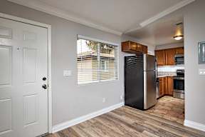 A kitchen with a black fridge and wooden floors.