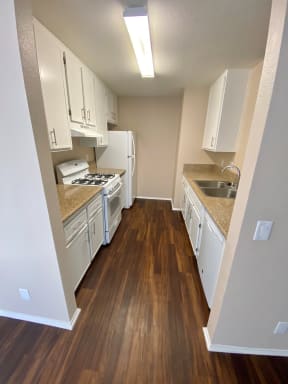 Modern, newly renovated kitchens with white appliances and cabinets at Grande Vista Apartments.