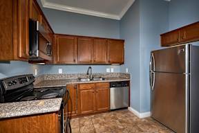 A kitchen with a stove, sink, and refrigerator.