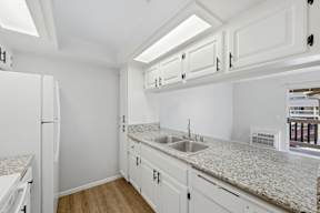 A kitchen with white cabinets and a granite countertop.