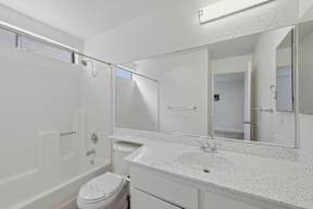 A white bathroom with a toilet, sink, and mirror.