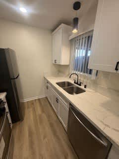A kitchen with white cabinets and a black fridge.