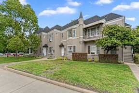 A large, well-maintained house with a grey exterior and a green lawn.