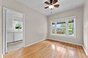 A room with a ceiling fan and a window overlooking a backyard.