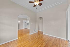 A room with a ceiling fan and wooden floors.