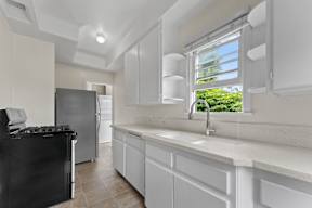 A kitchen with white cabinets and a black stove top oven.