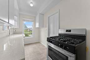 A modern kitchen with a stainless steel gas stove and a window overlooking the backyard.