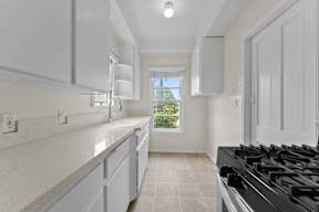 A kitchen with a black stove top oven and white cabinets.