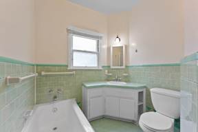 A bathroom with a white tub, toilet, and sink.