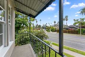 A balcony with a metal railing overlooks a street.