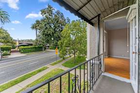 A balcony with a view of a street and trees.