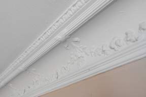 A white molding with carvings runs along the top of a wall.