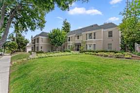 A large, well-maintained house with a green lawn in front.