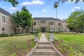 A large, well-maintained house with a front yard and a pathway leading to the entrance.