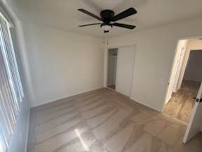 A room with a ceiling fan and carpeted floor.