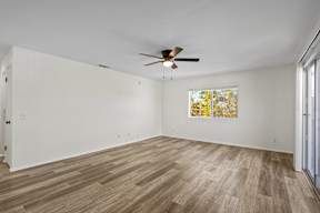 A room with a ceiling fan and a painting on the wall.