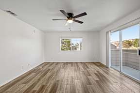 A room with a ceiling fan and wooden flooring.