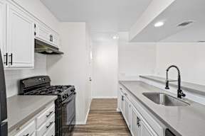 A kitchen with white cabinets and a black stove top oven.