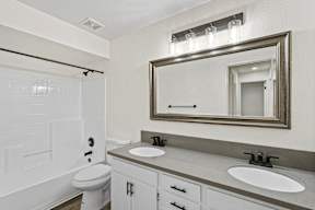 A bathroom with a toilet, sink, and mirror.