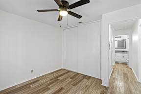 A room with a ceiling fan and wooden flooring.