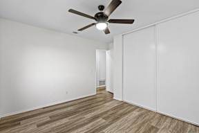 A room with a ceiling fan and wooden flooring.