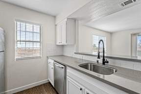 A kitchen with white cabinets and a stainless steel sink.