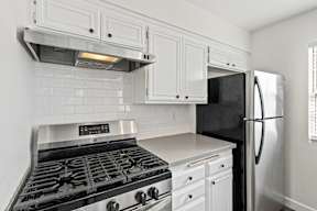 A black stove top oven with white cabinets above it.