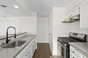A kitchen with white cabinets and a black stove top oven.