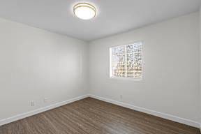 A room with a window and wooden flooring.