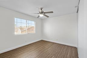 A room with a ceiling fan and a window with blinds.