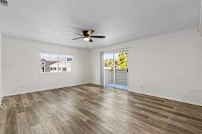 A room with a ceiling fan and sliding glass doors leading to a balcony.
