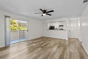 A room with a ceiling fan and sliding glass doors.